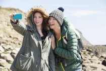 Madre e hija tomando selfie a orillas del mar - foto de stock