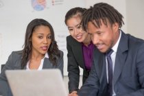 Uomo d'affari e donne d'affari, in carica, brainstorming, utilizzando il computer portatile — Foto stock
