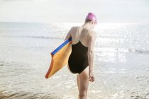 Mulher jovem carregando prancha de surf no mar — Fotografia de Stock