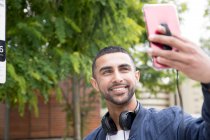 Молодой человек на улице, делает селфи с помощью смартфона — стоковое фото