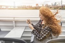 Jeune femme d'affaires sur le pont de ferry de passagers en utilisant un smartphone — Photo de stock