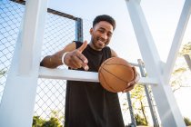 Retrato de un joven sonriente sosteniendo baloncesto - foto de stock