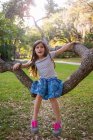Portrait of girl, outdoors, sitting on tree branch — Stock Photo