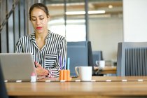 Geschäftsfrau sitzt am Schreibtisch und benutzt Laptop — Stockfoto