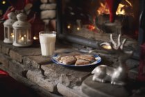 Bolachas e leite, para Papai Noel, deixados ao lado da lareira — Fotografia de Stock