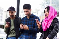 Drei Freunde in Reih und Glied schauen auf Smartphones — Stockfoto