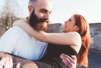 Homme barbu portant femme souriante dans les bras — Photo de stock