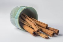 Cinnamon sticks spilling from bowl on white background — Stock Photo