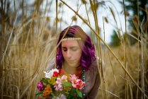 Portrait de Femme avec bouquet de fleurs parmi l'herbe haute — Photo de stock