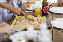 Mulher cortando pizza na mesa de almoço — Fotografia de Stock