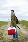 Молодая женщина-рыбак с удочкой, оглядываясь назад — стоковое фото