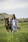 Junge Frau geht mit Pferd durch Feld — Stockfoto