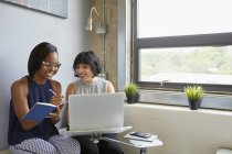 Two businesswomen working with laptop and notebook in modern office — Stock Photo