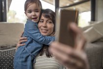 Mature woman taking selfie with daughter in living room — Stock Photo