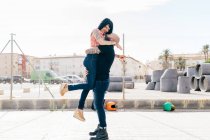 Mature hipster man lifting and hugging girlfriend in city — Stock Photo
