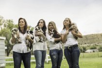 Retrato de mujer madura y mujeres jóvenes sosteniendo cachorros en el rancho, Bridger, Montana, EE.UU. - foto de stock