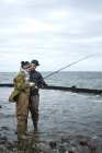 Young man teaching girlfriend fishing — Stock Photo