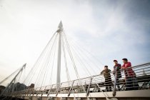 Três amigos, em pé na ponte, olhando para a vista, Golden Jubilee Footbridge, Londres, Inglaterra, Reino Unido — Fotografia de Stock