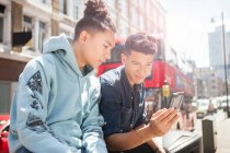 Dois jovens ao ar livre, olhando para o smartphone — Fotografia de Stock