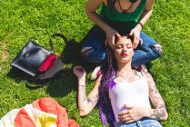 Mujer dando amigo cabeza masaje en hierba - foto de stock
