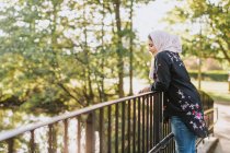 Молода жінка в хіджабі на мосту дивиться на — стокове фото