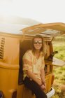 Portrait of young male surfer with long hair leaning against vintage recreational vehicle, Exeter, California, USA — Stock Photo