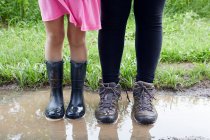 Dos chicas de pie en el barro, sección baja - foto de stock