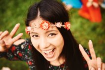 Portrait of young boho woman making peace sign at festival — Stock Photo