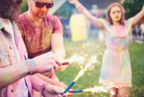 Young men covered in coloured chalk powder holding sparklers at festival — Stock Photo