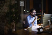 Молодий бізнесмен дивиться на комп'ютер на офісному столі вночі — стокове фото