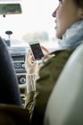 Femme tenant smartphone avec carte à l'écran dans la voiture — Photo de stock