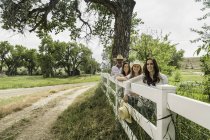 Retrato de pareja adulta e hijas apoyadas en la cerca del rancho, Bridger, Montana, EE.UU. - foto de stock