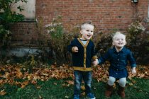 Glückliche männliche und weibliche Kleinkind-Zwillinge halten Händchen im Garten — Stockfoto