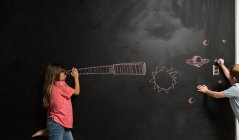 Девушка смотрит в воображаемый телескоп, нарисованный на доске — стоковое фото