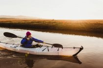 Mezzo kayak donna adulta sul fiume al tramonto, Morro Bay, California, Stati Uniti — Foto stock