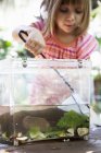 Дівчина з рибальською сіткою та пластиковим ставком на садовому столі — стокове фото