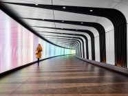 Vista trasera de la mujer caminando a través de la pasarela del túnel, London City Airport, Londres, Reino Unido - foto de stock
