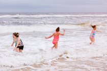 Три девочки, играющие на океанских волнах, остров Дофин, Алабама, США — стоковое фото