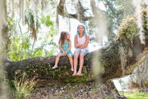 Girls sitting on old oak tree — Stock Photo