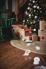 Arbre de Noël entouré de cadeaux, empreintes de pas du Père Noël menant vers l'arbre — Photo de stock