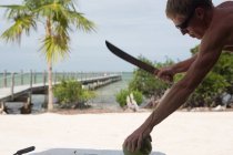 Visão lateral do homem vai cortar coco usando facão — Fotografia de Stock