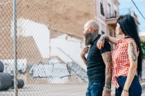 Reifes Hipster-Paar blickt über Maschendrahtzaun — Stockfoto