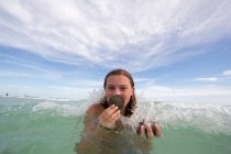 Portrait de jeune femme dans l'eau, tenant des coquillages — Photo de stock