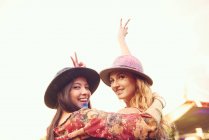 Portrait of two young female friends making peace sign at festival — Stock Photo
