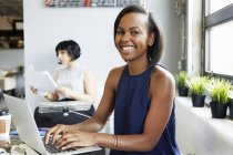 Портрет жінки, що працює на ноутбуці в сучасному офісі — стокове фото