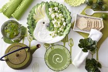 Overhead view of table with green pea soup, fresh salad and water biscuits — Stock Photo