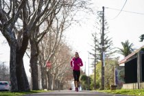 Vista frontale della giovane donna che fa jogging sulla strada — Foto stock
