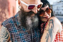 Зрелая татуированная пара хипстеров обнимается на тротуаре, крупным планом — стоковое фото
