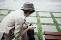 Молодой человек держит смартфон и ищет в сумке — стоковое фото
