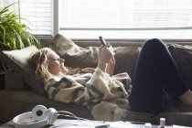 Femme utilisant un téléphone portable sur le canapé — Photo de stock